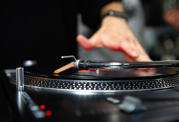 Disc jockey scratching vinyl records with turntable player on party in night club. Professional hip...