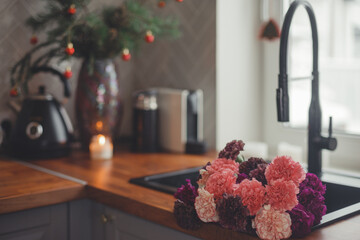 Cozy home lifestyle: wooden table top with beautiful carnation flowers and Christmas decorations.