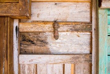 Traditional hand shaped rusty iron door knocker on retro vintage style weathered wooden entrance door