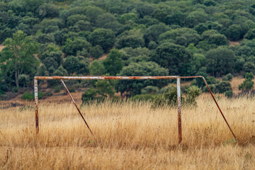 Old rusty abandoned goal over abandoned field
