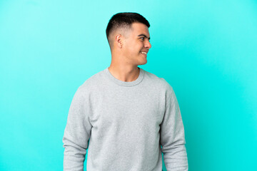 Young handsome man over isolated blue background looking side