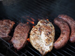 Chicken beef and sausage on a charcoal grill 