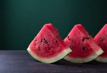 Pieces of refreshing watermelon on a dark wood background. Close-up photo.