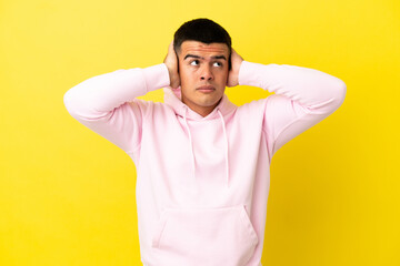 Fototapeta na wymiar Young handsome man over isolated yellow background frustrated and covering ears