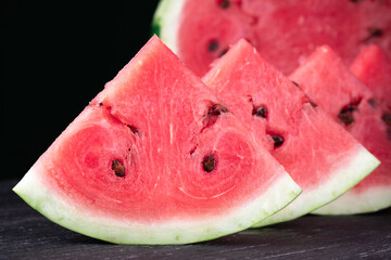 Pieces of refreshing watermelon on a dark wood background. Close-up photo. Fruit texture