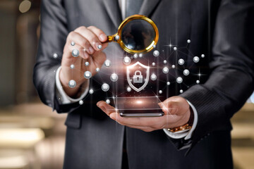 Businessman with a magnifying glass watches the protection of the network in a mobile device.
