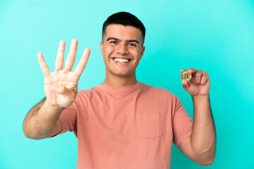 Young handsome man holding a Bitcoin over isolated blue background happy and counting four with fingers