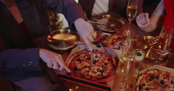 Close up of hand using knife to cut pizza on dining table with friends in restaurant celebrate festival. Friends Happiness Enjoying Dinning Eating. Various kinds food on wooden table