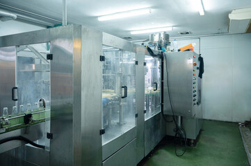 Beverage bottling room with automatic machinery and control panel in production line at processing factory