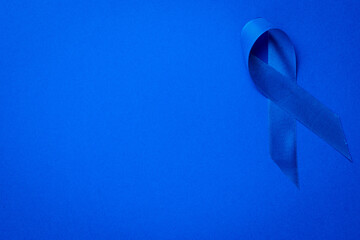 Blue prostate ribbon. Awareness of men health in November with blue prostate cancer ribbon isolated on deep blue background. November and International Mens Day.