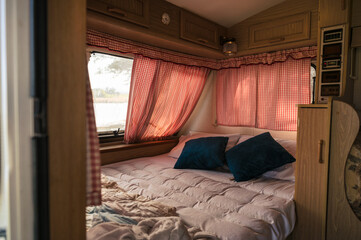 Inside of camper van with bed, pillow, curtain on window at campsite