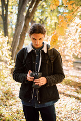 Photographer shooting pictures in autumn park. Portrait of photographer with modern camera looking through shot photos