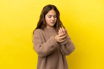 Little caucasian girl isolated on yellow background suffering from pain in hands