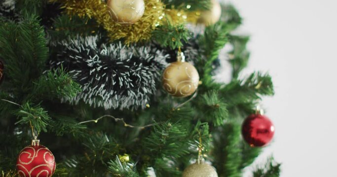 Video of christmas tree decorated with baubles on white background