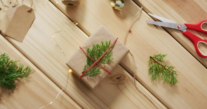 Video of christmas decorations with present and scissors on wooden background