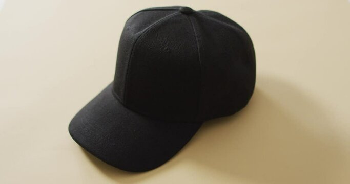 Video of close up of black baseball cap lying on pale table top