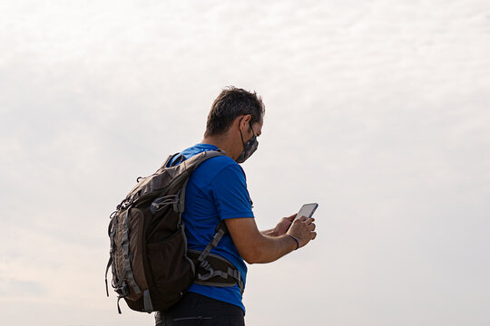 Young boy with backpack looking at his mobile phone
