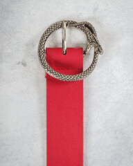 Beautiful red leather belt with silver metal buckle in the shape of snake eating itself (ouroboros)...
