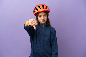 Little caucasian girl isolated on purple background showing thumb down with negative expression