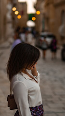 Fototapeta premium girl on the street, talking on the phone in Mdina during twilight