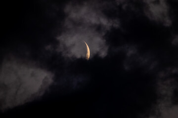 Obraz na płótnie Canvas crescent moon behind dark clouds