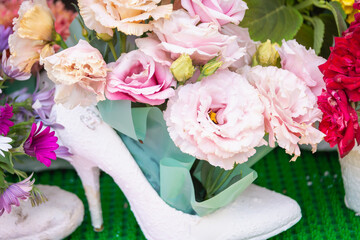 A bouquet of flowers in a white woman's shoe.