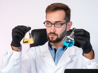Biological laboratory assistant with test tubes in his hands. Young biologist in a white coat....