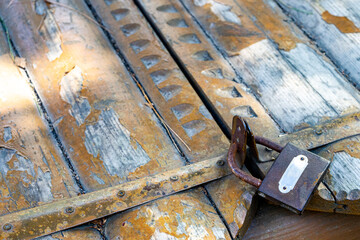 Old wooden door closed with a rusty metal pad. Close up