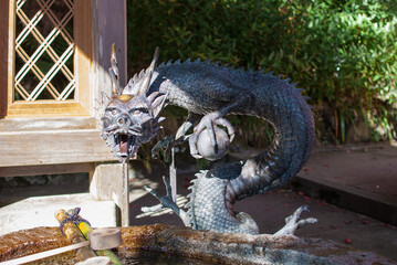 Traditional Japanese dragon statue in the entrance of the temple where hand wash equipment is located