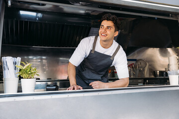 Portrait of a smiling food truck owner wearing apron leaning counter - Powered by Adobe
