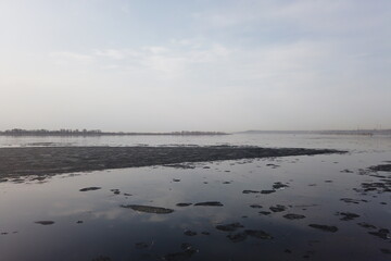 spring flood of the lake, leaves float on the water, ice melts, oil stains