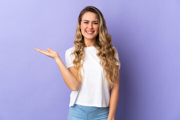 Fototapeta na wymiar Young Brazilian woman isolated on purple background holding copyspace imaginary on the palm to insert an ad