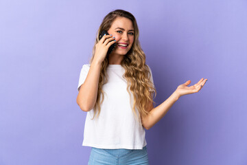 Young Brazilian woman isolated on purple background keeping a conversation with the mobile phone with someone