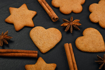 Gingerbread cookies and spices on black slate