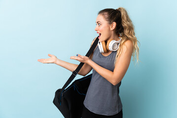 Young sport Brazilian woman with sport bag isolated on blue background with surprise expression while looking side