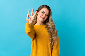 Young Brazilian woman isolated on blue background happy and counting three with fingers