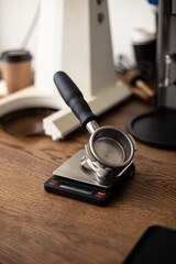 Empty holder for coffee on electronic scales against the background of coffee grinders.