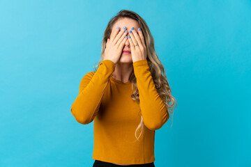 Young Brazilian woman isolated on blue background covering eyes by hands