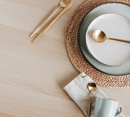Modern ceramic tableware top view on beige wooden table with copy space.  Trendy plates, cutlery and linen napkins scandinavian style.Space for text or menu . Business food brand template.