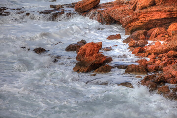 Red Coast Rocks. Salty water with  sea foam in Syros island,Greece. Stock Image