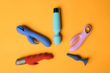 An abundance of colorful dildos on a yellow background. Clitoral massager, sex toys for maintaining...