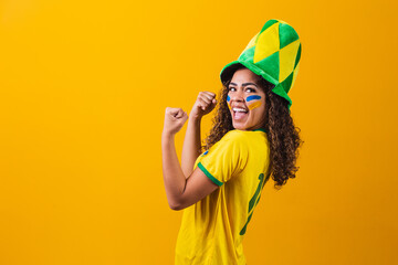 Brazilian supporter. Brazilian woman fan celebrating on soccer or football match on yellow background. Brazil colors. Yes!