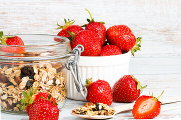 granola in a jar and fresh strawberries on a wooden background