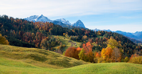 idyllic autumn landscape upper bavaria, view over green hilly pasture and colorful forest to mountains