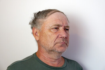 portrait of a disgruntled elderly frowning man on a light background
