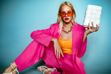 Fashionable confident woman wearing trendy summer suit, sunglasses, holding white cassette bag,...
