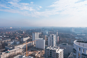 View of the construction of multi-storey buildings against the background of the blue morning sky. Calm cityscape, balcony view.