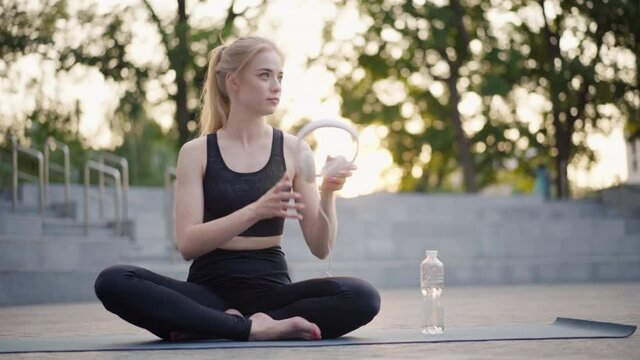 Yoga and Meditation in Modern City Caucasian Woman Relax Lotus Position Sitting Yoga Mat Outdoors Summer Park on Concrete floor Young Adult Fit Female Relaxing after Yoga Practice Workout Siddhasana