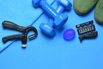 
Dumbbells, manual training grip and various accessories, on a blue background. Zenith view and copy space.
