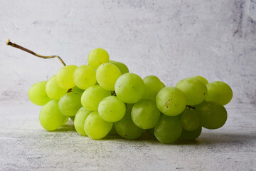 Bunch of white grapes, on stone background in gray tones. Copy space.